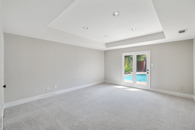 empty room with a tray ceiling and light colored carpet