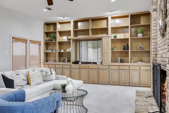 carpeted living room with a fireplace, ceiling fan, crown molding, and sink