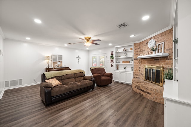 living room featuring dark wood-type flooring, ornamental molding, a fireplace, and ceiling fan