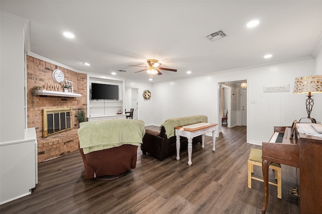 living room with a fireplace, dark hardwood / wood-style floors, ornamental molding, and ceiling fan