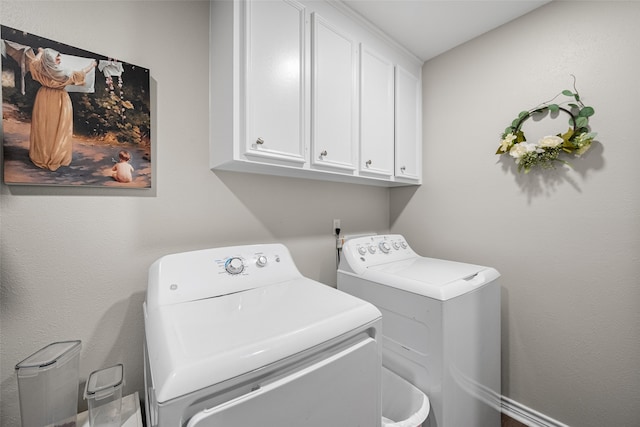 laundry area featuring washing machine and clothes dryer and cabinets