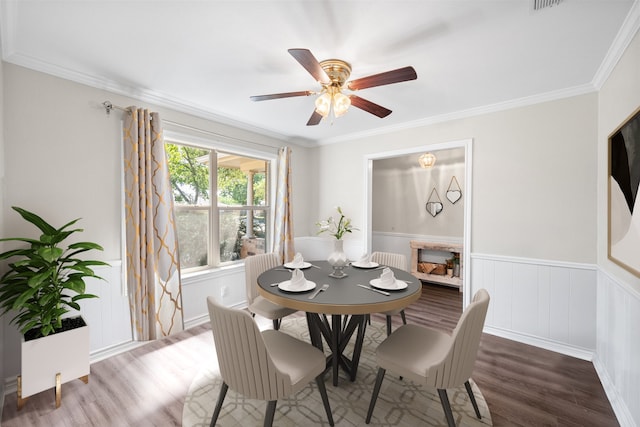 dining room with dark wood-type flooring, crown molding, and ceiling fan