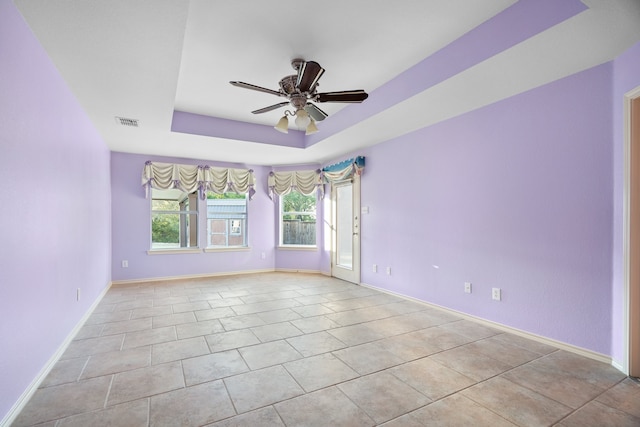 unfurnished room featuring light tile patterned floors, a raised ceiling, and ceiling fan