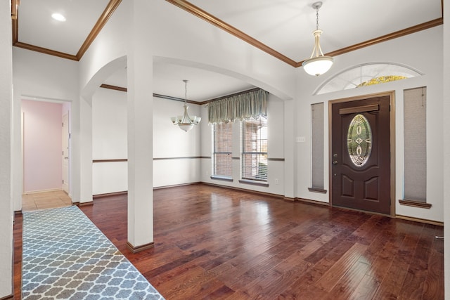 entrance foyer featuring ornamental molding, dark wood-type flooring, and a chandelier