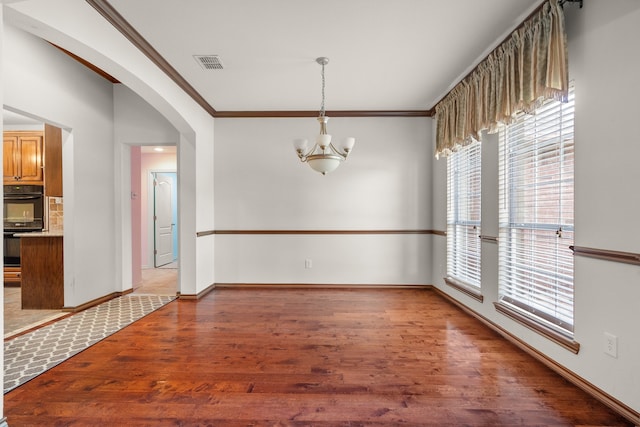 unfurnished dining area with crown molding, a chandelier, and hardwood / wood-style flooring