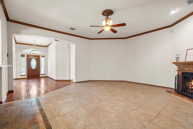 7710 Valley Ridge Dr, Northlake, TX 76247 - unfurnished living room featuring a ceiling fan, baseboards, ornamental molding, arched walkways, and a lit fireplace