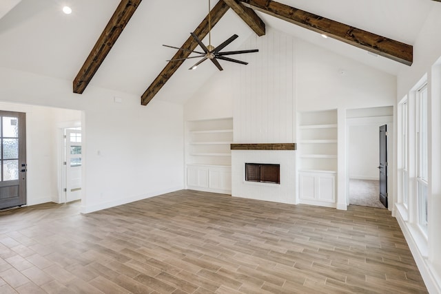 unfurnished living room with ceiling fan, beamed ceiling, high vaulted ceiling, a fireplace, and light hardwood / wood-style floors