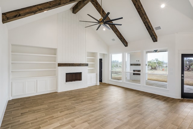 unfurnished living room featuring a fireplace, beam ceiling, and light hardwood / wood-style floors