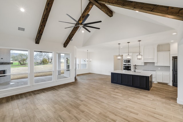 kitchen featuring pendant lighting, sink, a kitchen island with sink, high vaulted ceiling, and light hardwood / wood-style floors