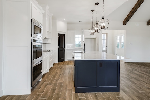 kitchen featuring appliances with stainless steel finishes, dark wood-type flooring, a kitchen island with sink, and white cabinetry