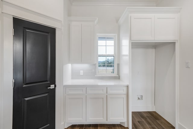 kitchen featuring tasteful backsplash, dark hardwood / wood-style flooring, ornamental molding, and white cabinets