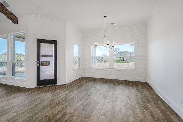 unfurnished dining area featuring a notable chandelier, plenty of natural light, hardwood / wood-style floors, and lofted ceiling with beams