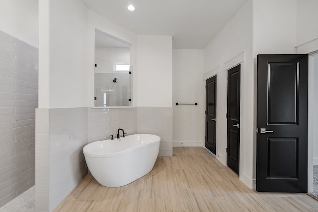 bathroom with hardwood / wood-style flooring, tile walls, and shower with separate bathtub