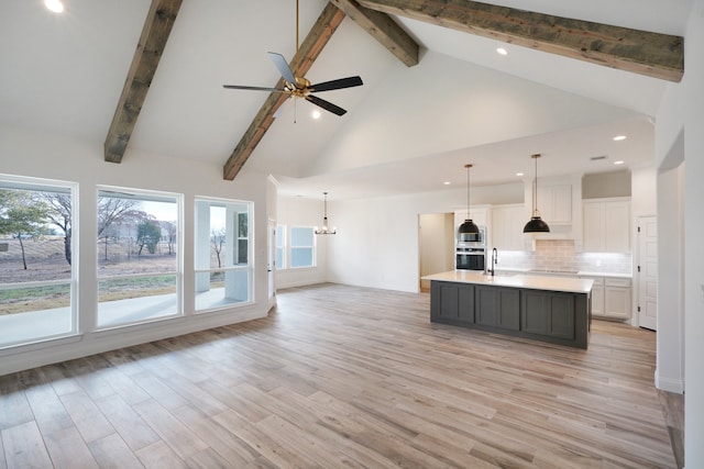 kitchen with beamed ceiling, light hardwood / wood-style flooring, high vaulted ceiling, a large island, and white cabinetry