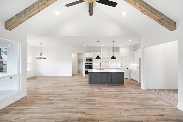 kitchen with pendant lighting, an island with sink, light hardwood / wood-style floors, and white cabinetry