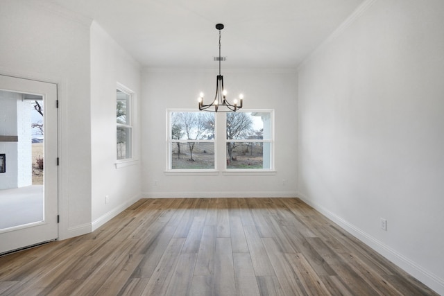 unfurnished dining area with a notable chandelier, crown molding, and hardwood / wood-style floors