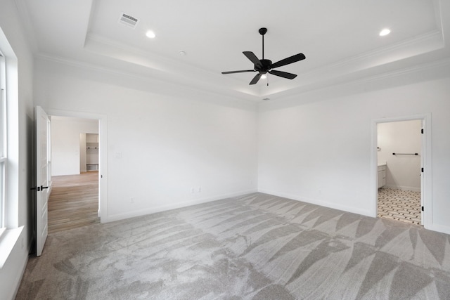 unfurnished bedroom with crown molding, a tray ceiling, ensuite bath, and ceiling fan