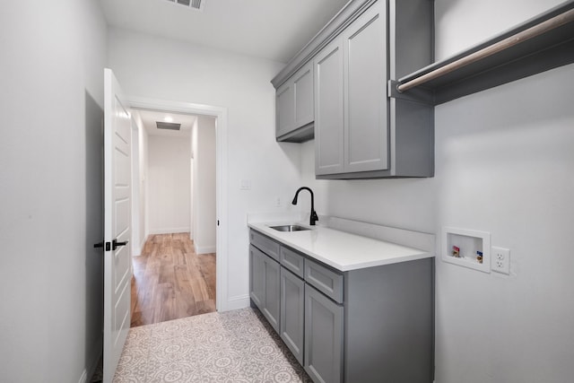 laundry area with light hardwood / wood-style flooring, cabinets, hookup for a washing machine, and sink