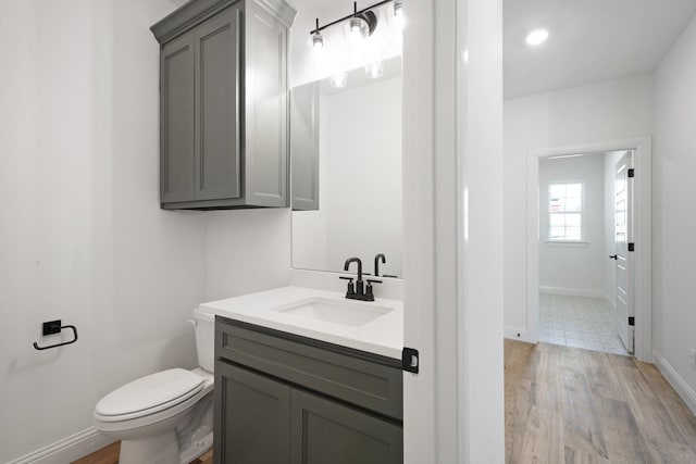 bathroom featuring wood-type flooring, vanity, and toilet