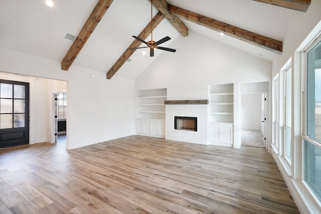 unfurnished living room with high vaulted ceiling, beam ceiling, light wood-type flooring, and ceiling fan