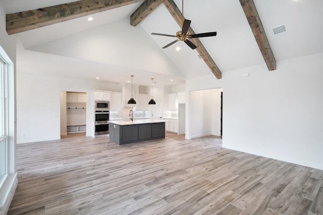 unfurnished living room featuring light hardwood / wood-style floors, beamed ceiling, ceiling fan, sink, and high vaulted ceiling