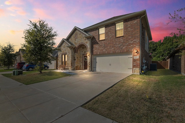 view of front of house with a lawn, a garage, and central air condition unit