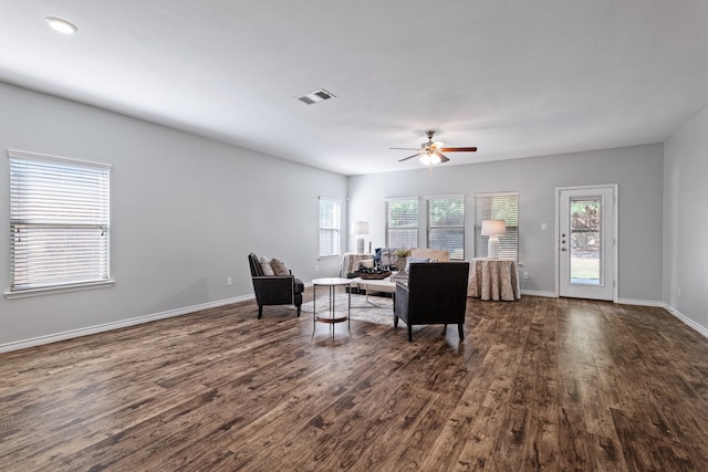 living room featuring a wealth of natural light, ceiling fan, and dark wood-type flooring