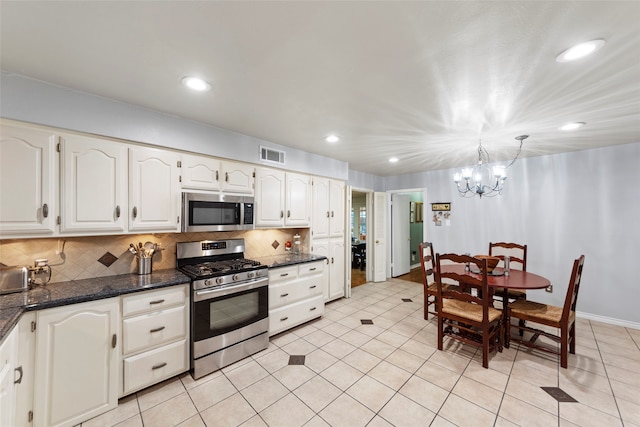 kitchen with tasteful backsplash, hanging light fixtures, white cabinetry, stainless steel appliances, and a chandelier