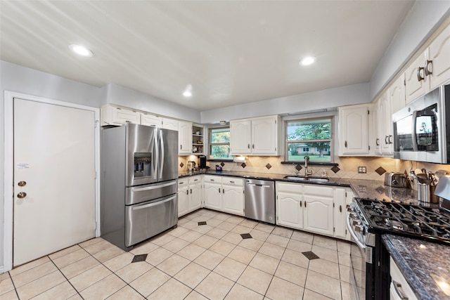 kitchen featuring backsplash, sink, white cabinets, light tile patterned flooring, and appliances with stainless steel finishes