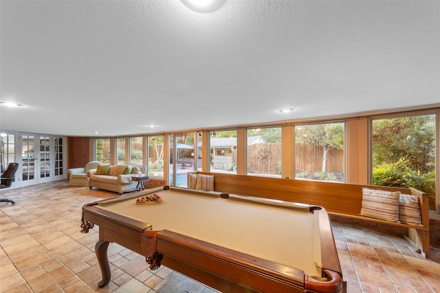 rec room with pool table, light tile patterned floors, a textured ceiling, floor to ceiling windows, and french doors