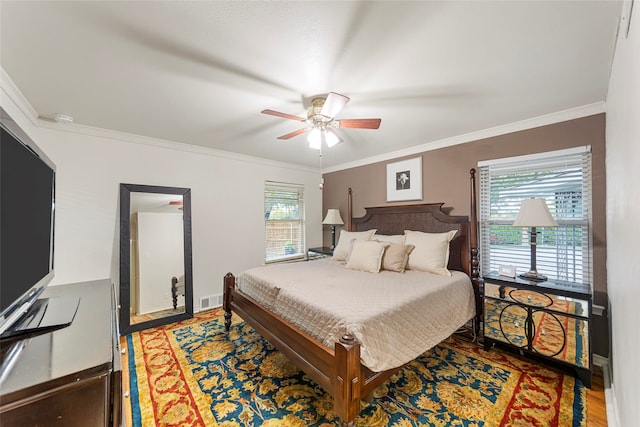 bedroom featuring hardwood / wood-style floors, crown molding, and ceiling fan