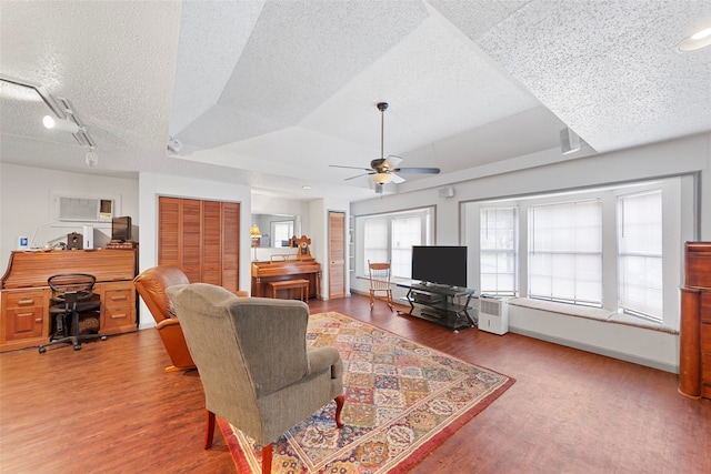 living room with a textured ceiling, wood-type flooring, and ceiling fan