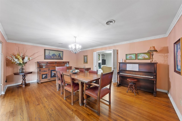 dining space featuring crown molding, an inviting chandelier, and hardwood / wood-style floors