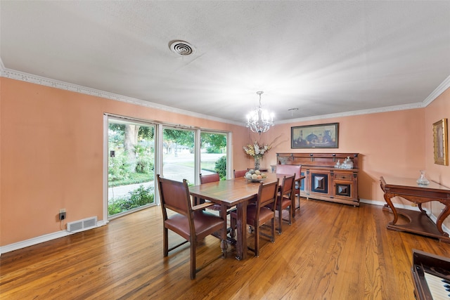 dining area featuring a notable chandelier, ornamental molding, light hardwood / wood-style flooring, and a textured ceiling