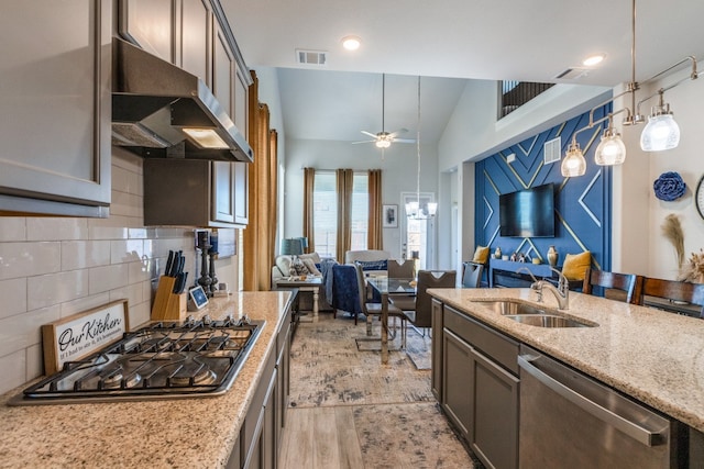 kitchen featuring light stone counters, stainless steel appliances, sink, light hardwood / wood-style floors, and vaulted ceiling