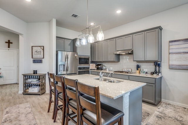 kitchen featuring light hardwood / wood-style floors, gray cabinetry, pendant lighting, decorative backsplash, and appliances with stainless steel finishes