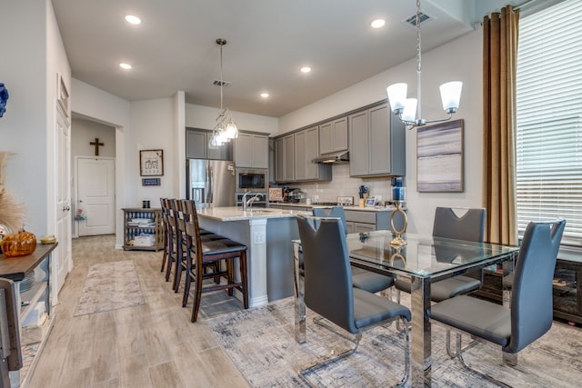 kitchen featuring light hardwood / wood-style floors, gray cabinets, decorative light fixtures, and stainless steel appliances