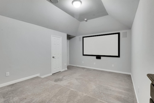 cinema room with vaulted ceiling and light colored carpet