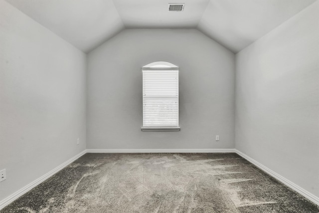 empty room featuring carpet and vaulted ceiling