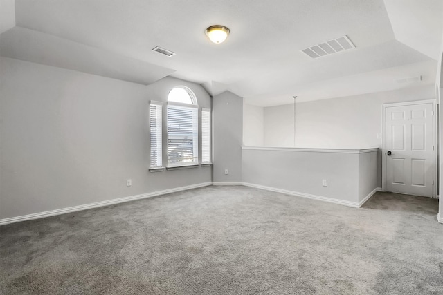 carpeted spare room with vaulted ceiling