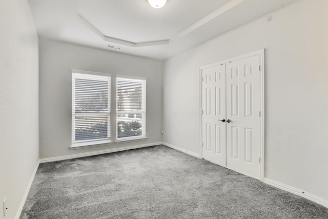 unfurnished bedroom featuring a closet, carpet floors, and a raised ceiling