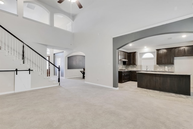 unfurnished living room featuring a high ceiling, a barn door, light carpet, and ceiling fan