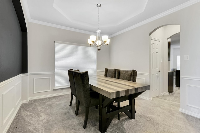 carpeted dining area with crown molding, a chandelier, and a raised ceiling