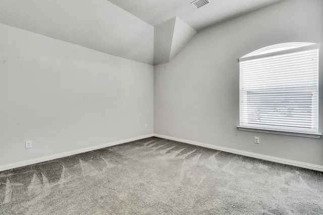 carpeted spare room featuring lofted ceiling