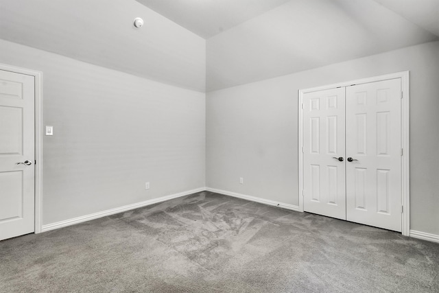 unfurnished bedroom featuring a closet, carpet flooring, and lofted ceiling