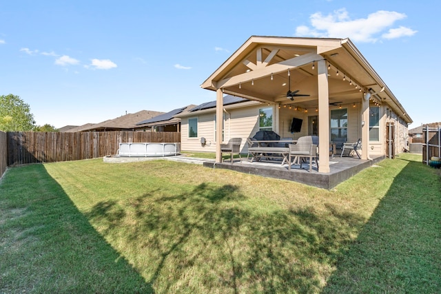 back of property with ceiling fan, a yard, and a patio