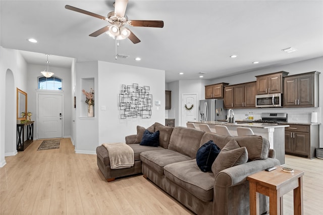 living room with ceiling fan, light hardwood / wood-style flooring, and sink