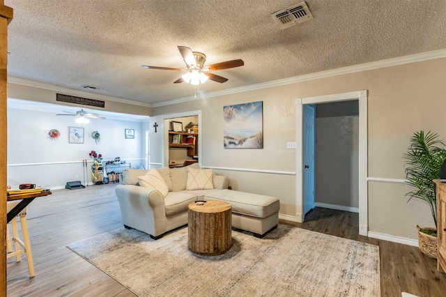 living room featuring crown molding, hardwood / wood-style floors, and a textured ceiling