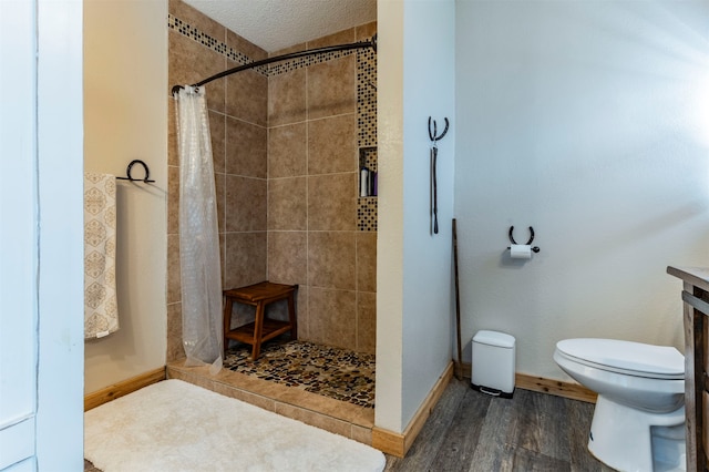 bathroom featuring toilet, hardwood / wood-style floors, a textured ceiling, and a shower with shower curtain