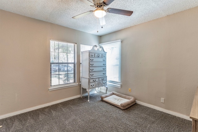 unfurnished bedroom featuring ceiling fan, a textured ceiling, and dark colored carpet